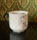 Stor antikk bartekopp i hvitt steingods/porselen rikt dekorert med blomstermotiv, tekst og gullkant Tyskland 1890-tallet thumbnail