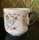 Stor antikk bartekopp i hvitt steingods/porselen rikt dekorert med blomstermotiv, tekst og gullkant Tyskland 1890-tallet thumbnail