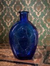 Flaske i koboltblått glass relief dekor ørn overflødighetshorn thumbnail